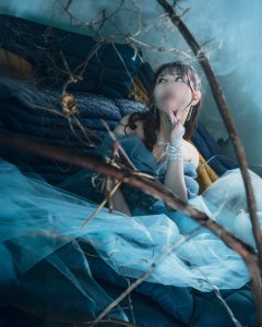 福岡の廃墟スタジオ『朝日陸運大川営業所』にて、フォトグラファー赤木友厚が撮影したポートレート。青いドレスを着たモデルAOIさんが、ガレキや枯れ枝の散乱する空間で、顎に手を当てて上を見上げている。青い光とスモークがちゃんみな『ハレンチ』MVの退廃的な世界観を再現している。顔にはぼかし処理。