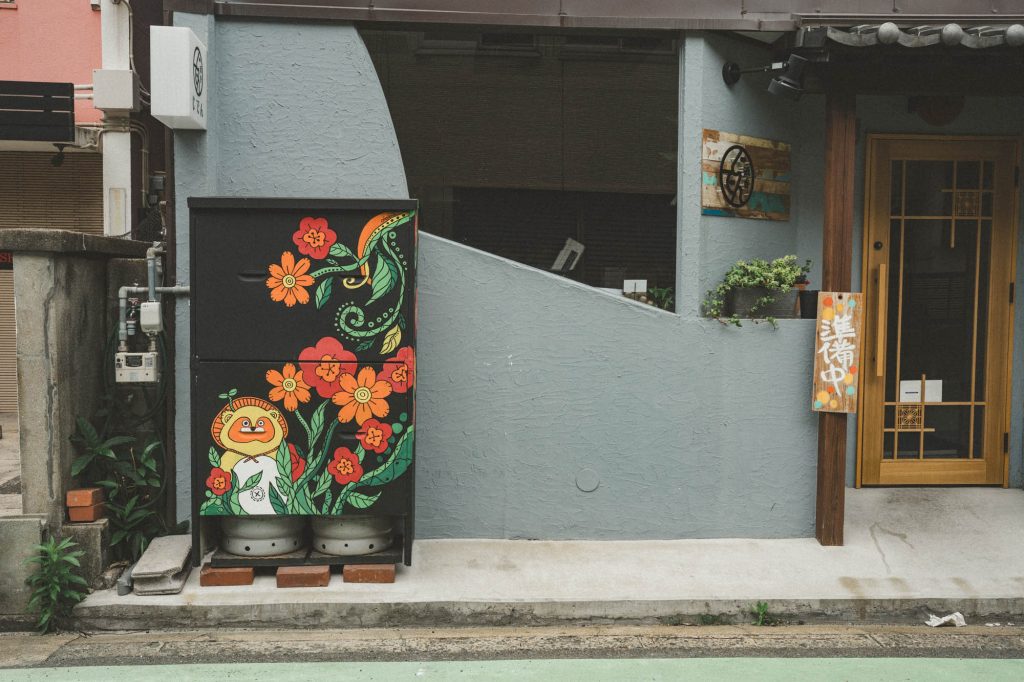 大宮の街角、グレーの壁に描かれた色鮮やかなタヌキと花のイラスト。