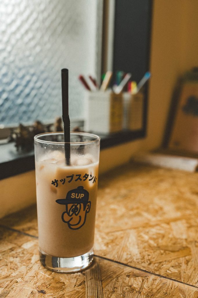 「サップスタンド」のロゴ入りグラスに注がれたアイスラテ。