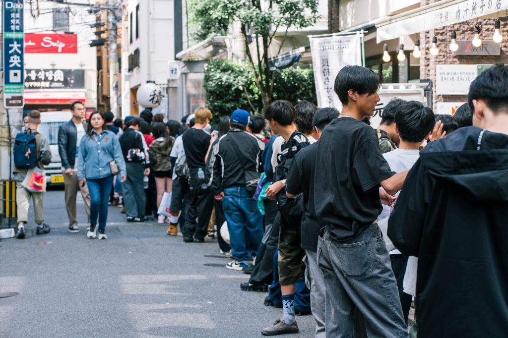 福岡市大名の大名口付近で、行列を作る若者たちと賑やかな街並みのストリートスナップ。