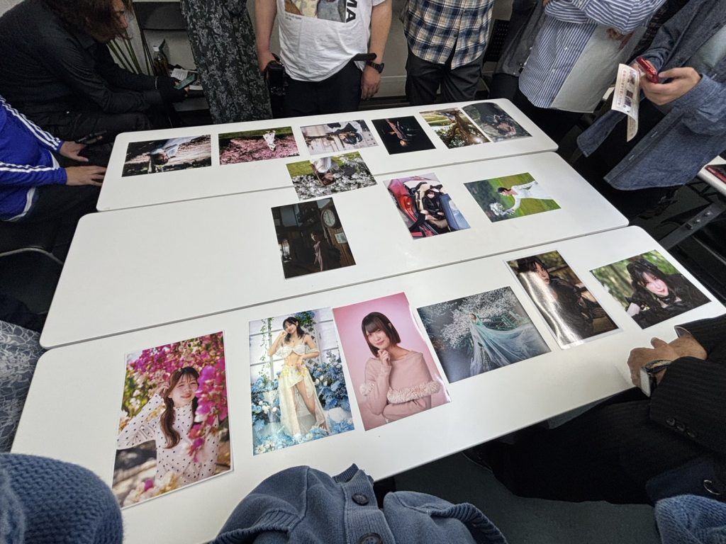 会議室の机の上に、様々なポートレート写真のA4プリントが並べられている様子