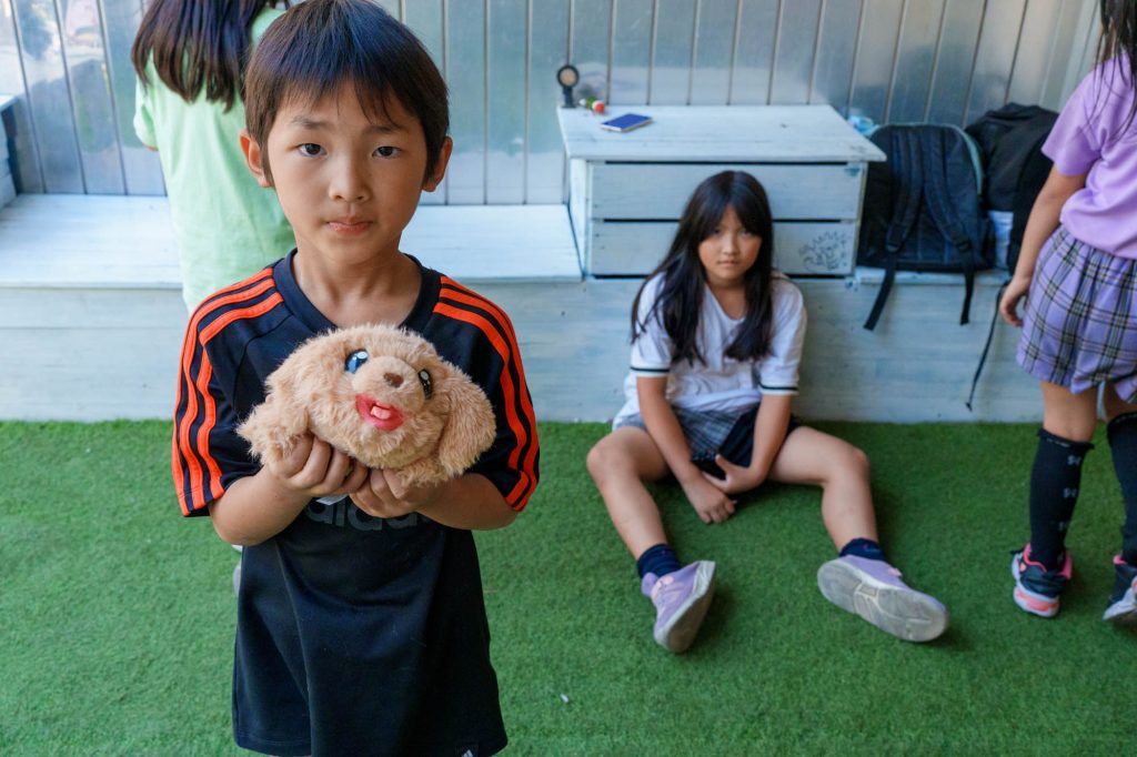 「おじちゃん、これ見て!」と、お気に入りのぬいぐるみを自慢しにきてくれた地元の少年。こういう日常の風景が普通に溶け込むのが、KMYの最高の魅力です。