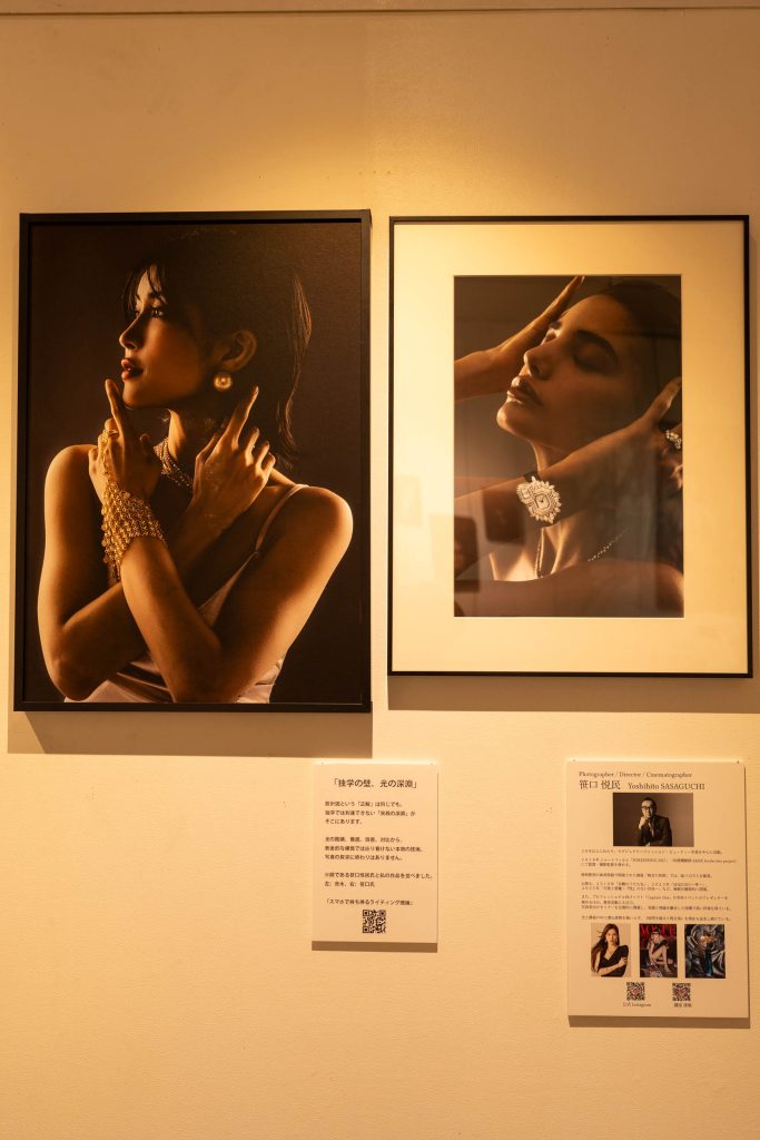 写真展会場の壁に並べて展示された2枚のポートレート作品。左側はネオンブルーのライティングが特徴的な赤木友厚の作品、右側はクラシカルなモノクロームの笹口悦民の作品。それぞれの下にライティング設計図入りのキャプションが添えられている。