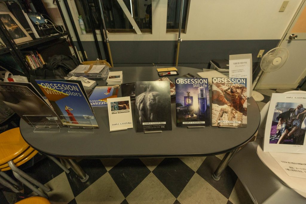 テーブルの上に並べられた笹口悦民氏の写真集「OBSESSION」やポートフォリオ。手前には作品プリントも見える。