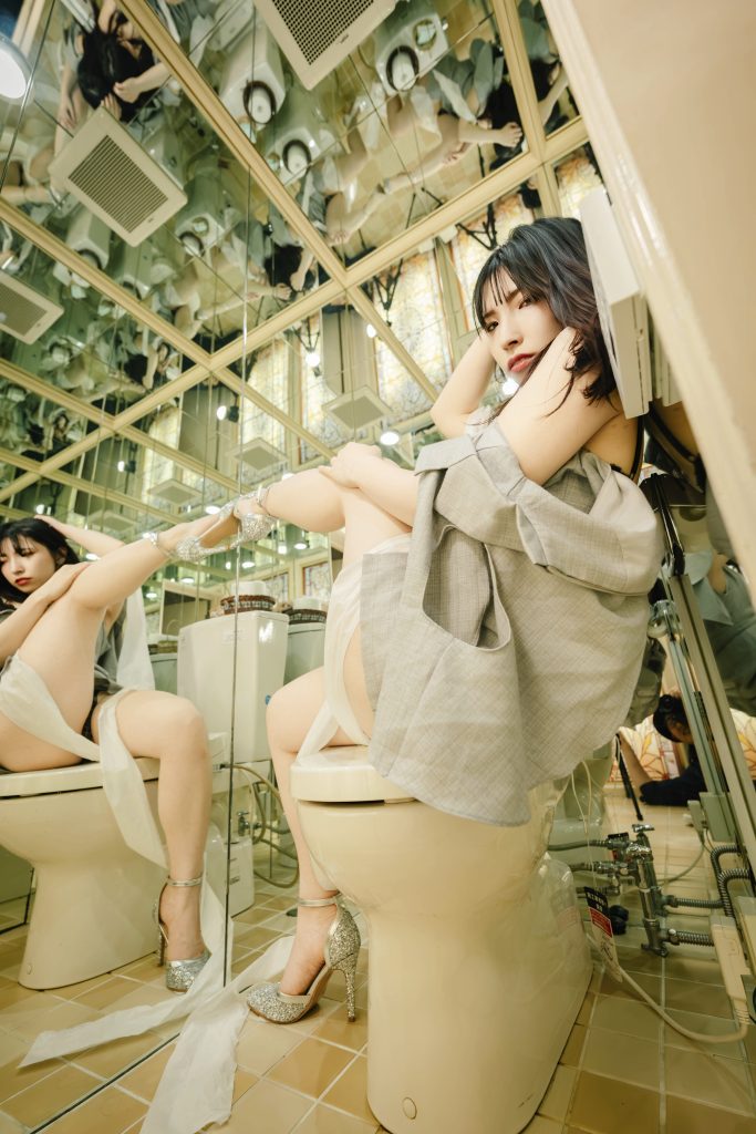 福岡のタバサホテルラテンの鏡張りの部屋でトイレットペーパーを絡ませてポーズをとるグラビアモデルと、それを撮影するフォトグラファー赤木友厚の作品
